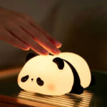 Cute silicone sleeping panda night lamp with soft warm glow on bedside table