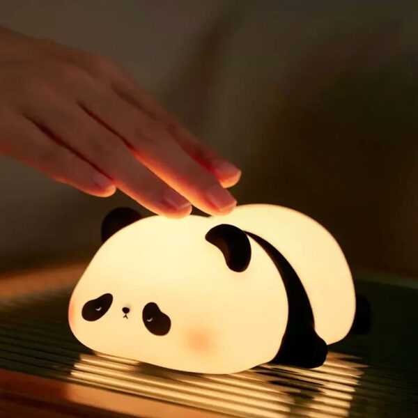 Cute silicone sleeping panda night lamp with soft warm glow on bedside table